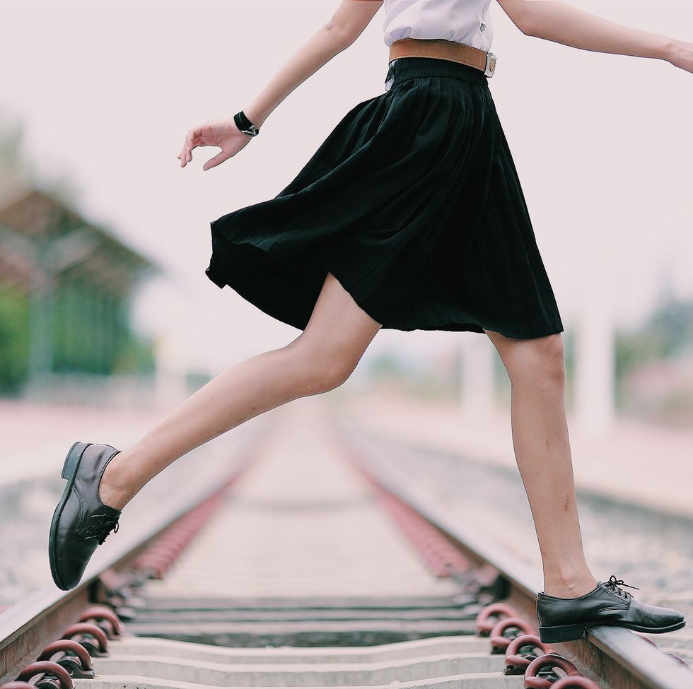 low section of woman crossing railroad track