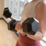 low section of woman exercising with dumbbells at home