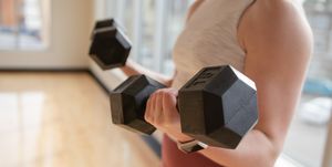 low section of woman exercising with dumbbells at home