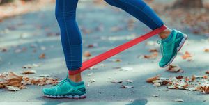 low section of woman exercising with resistance band on road during autumn