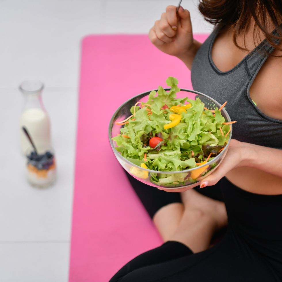 low section of woman having breakfast while sitting in yoga studio