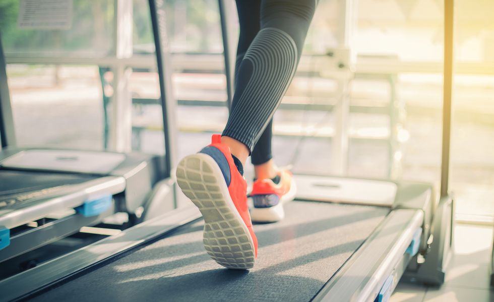 Low Section Of Woman Running On Treadmill In Gym