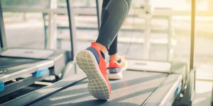 Low Section Of Woman Running On Treadmill In Gym