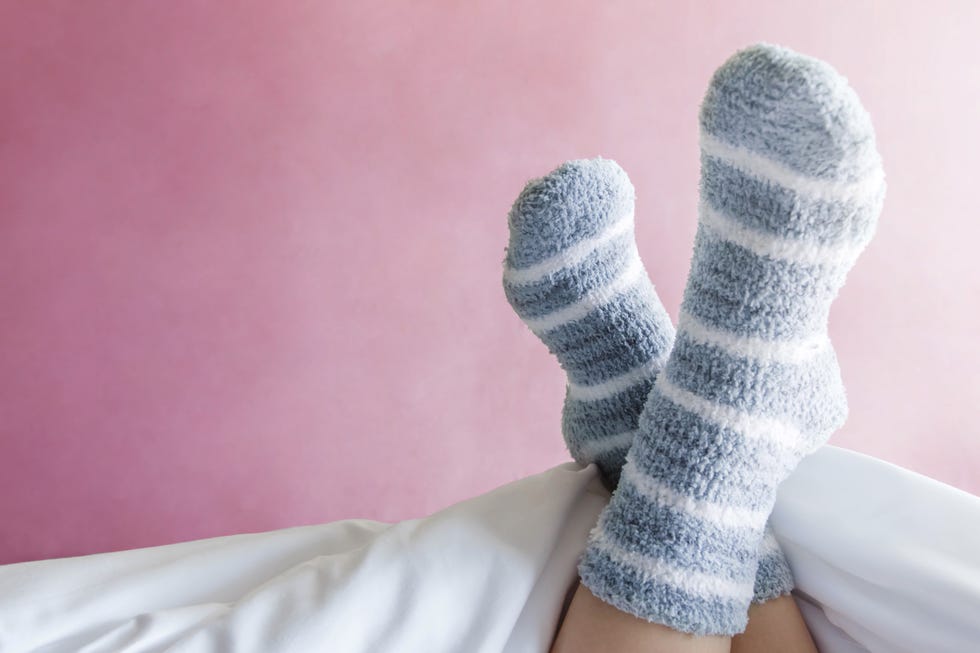 Low Section Of Woman Wearing Socks Against Wall At Home