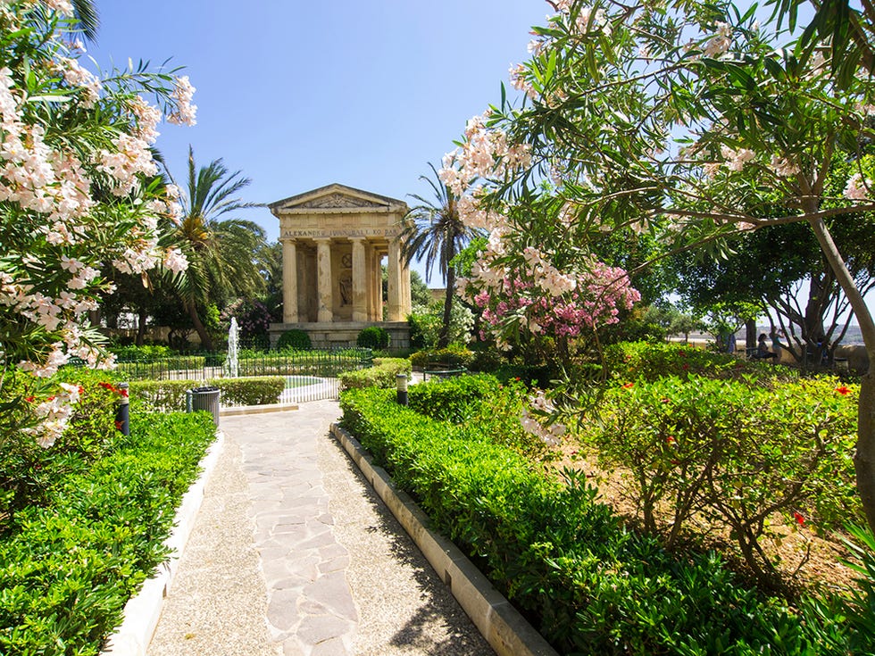 a beautiful lower barrakka garden in valletta which is the fortress city and malta's capital located on island in mediterranean sea  it has impressive bastions, forts and cathedrals and is considered as european art city and a world heritage city view from entrance, in background is beautiful view of three cities