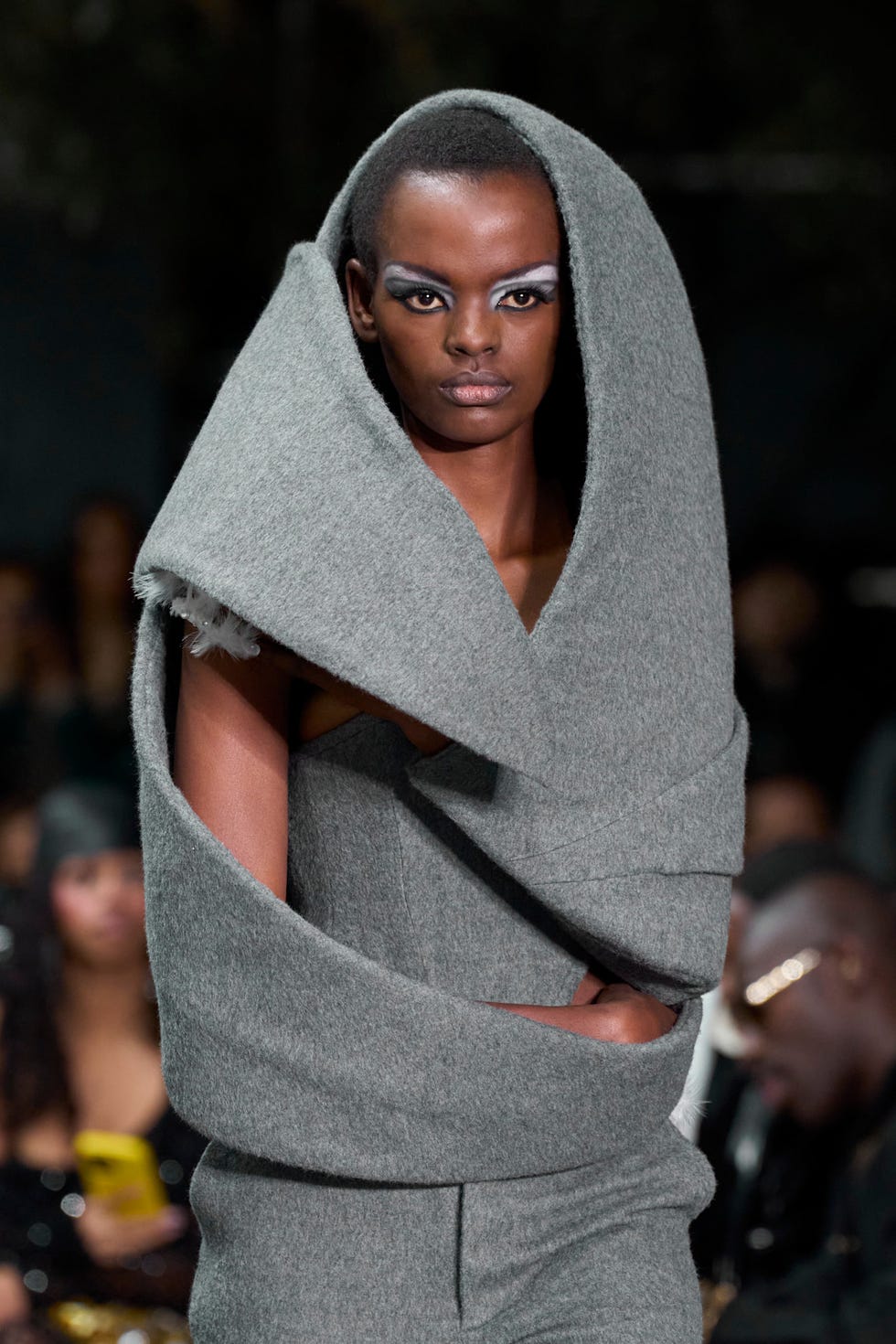 Fashion model showcasing a unique gray garment at a runway event