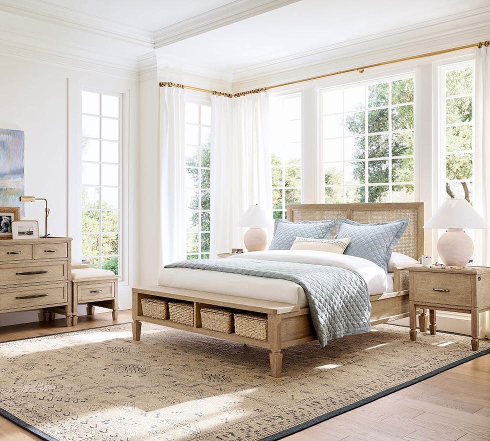 brightly lit modern bedroom featuring a bed with a quilt wooden nightstands and decorative elements