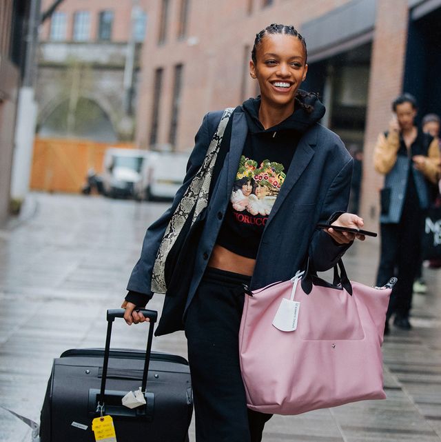 a model carries two pieces of luggage to illustrate a guide to the best luggage on amazon 2022