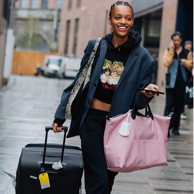 a model carries two pieces of luggage to illustrate a guide to the best luggage on amazon 2022