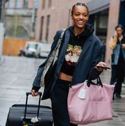 a model carries two suitcases to illustrate a guide to the best gifts for travelers in 2022