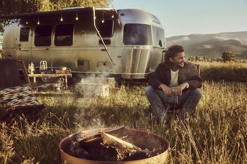 luke grimes in front of airstream camper