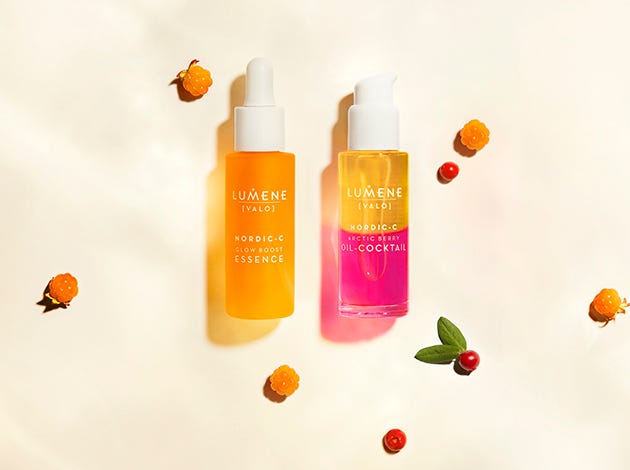 orange, pink and white lumene skincare product bottles on a light peach background with red and orange berries