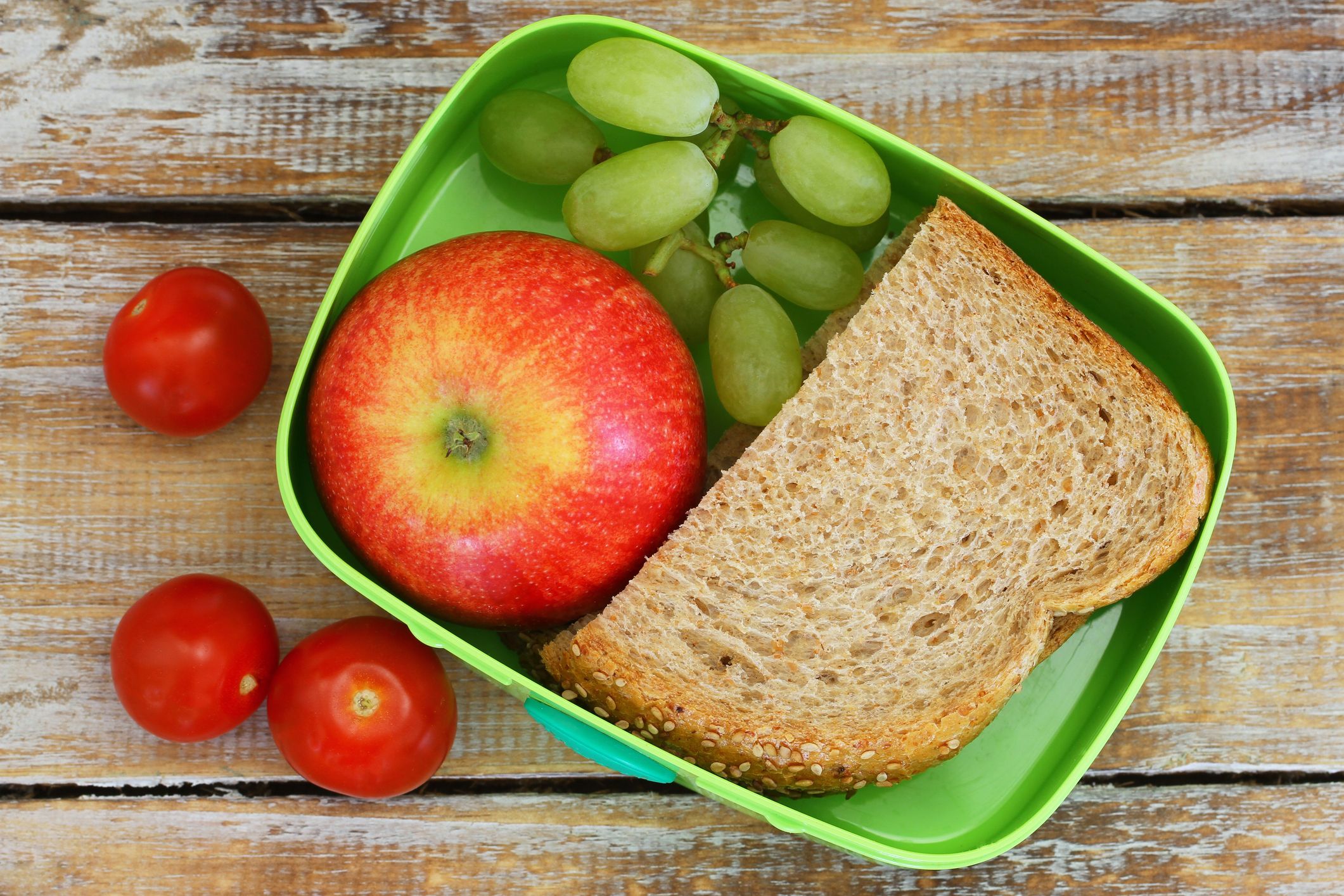 Lunch box consisting of wholegrain sandwich, fruit and cherry tomatoes
