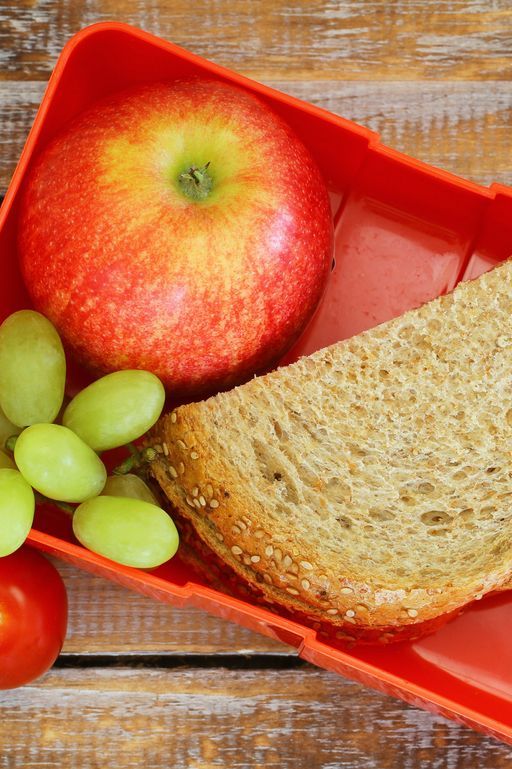 Lunch box with brown bread sandwich, apple, grapes and tomatoes
