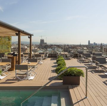 a rooftop deck with pool with chairs and a bar with views of the city