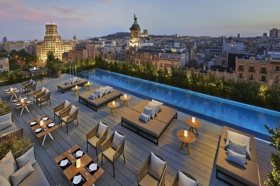 a rooftop pool with seating and views of the city in the background