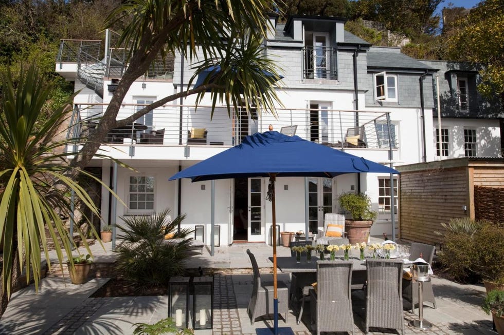 a patio with tables and chairs outside of a house