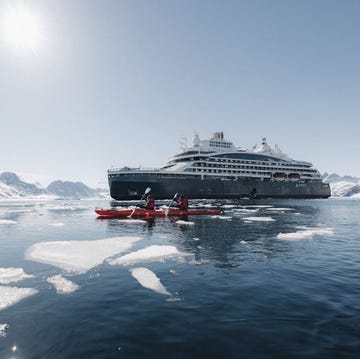 a boat in the water with a large cruise ship in the background a boat in the water with a large cruise ship in the background