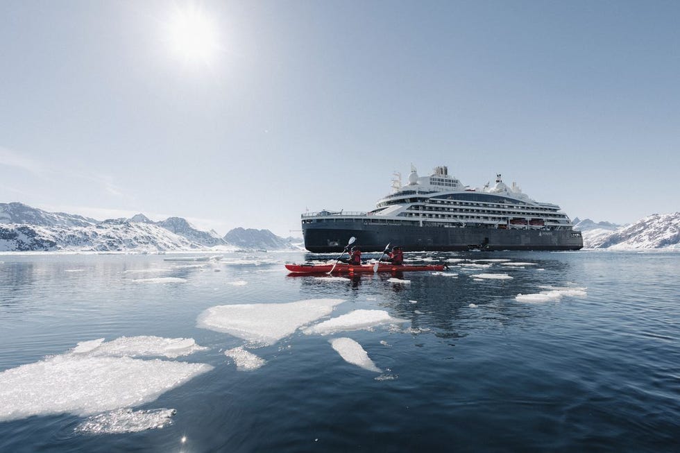 a boat in the water with a large cruise ship in the background