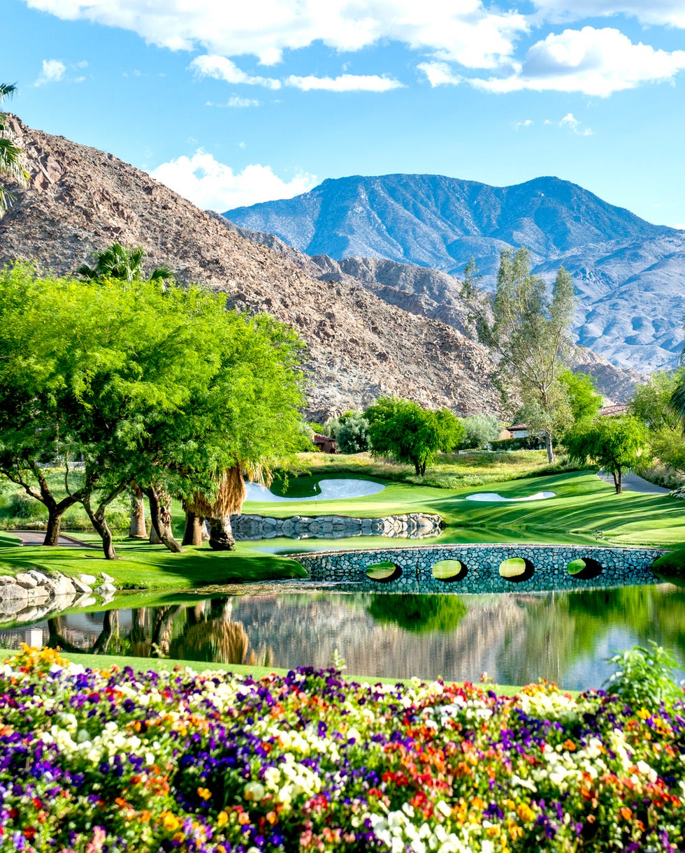 a luxury golf course with flowers and a bridge