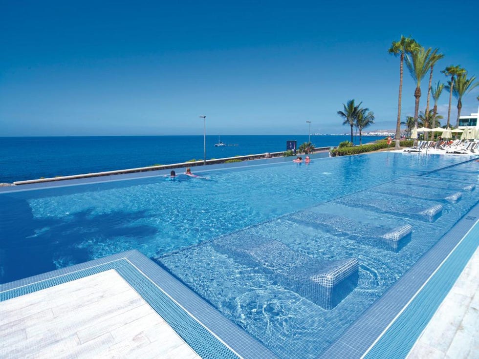 a pool overlooking the sea at hotel riu palace meloneras