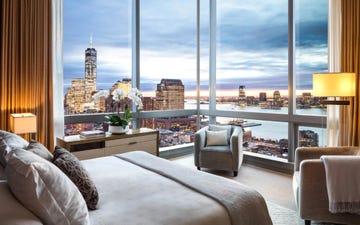 a room with a large corner window and a bed with a view of a city