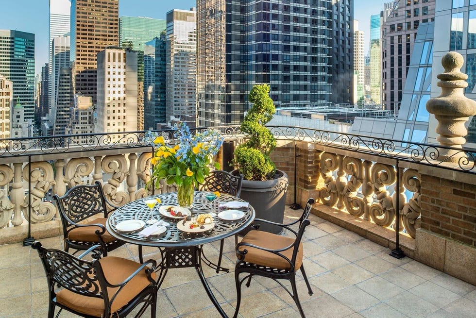 an outdoor terrace with table and chairs with a city skyline in the background