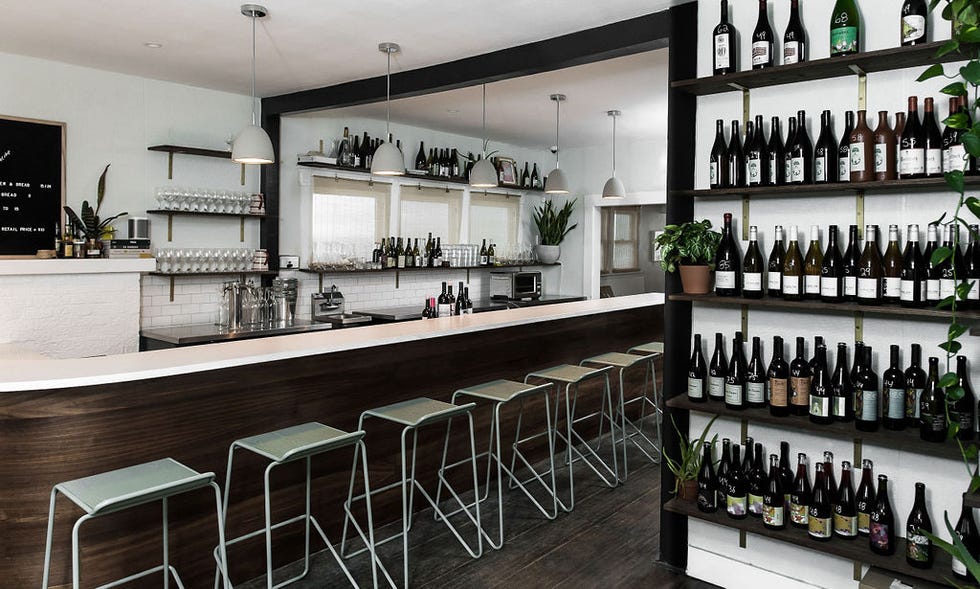 a bar with stools and shelves with bottles of wine