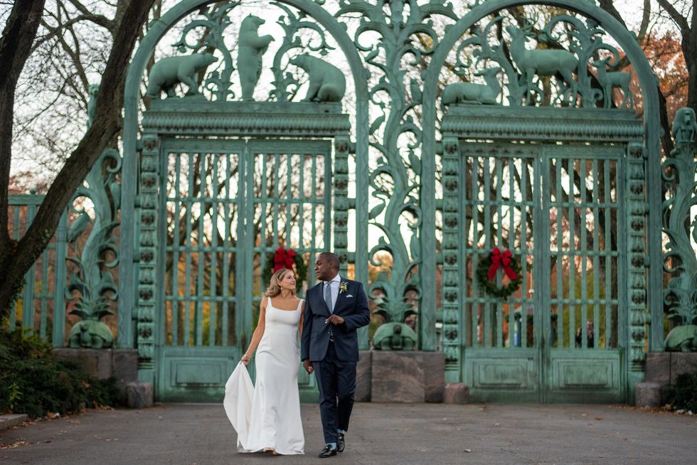 a man and woman posing for a picture in front of a gate