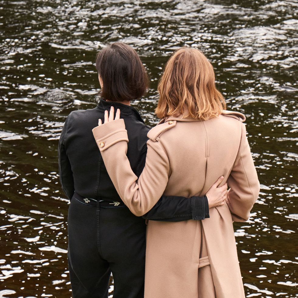 a man and woman hugging in front of a body of water