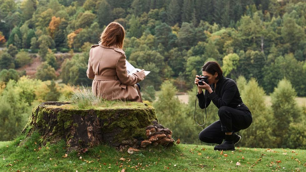 a woman taking a picture of a man sitting on a rock