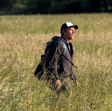 person walking through a tall grassy field with a backpack person walking through a tall grassy field with a backpack