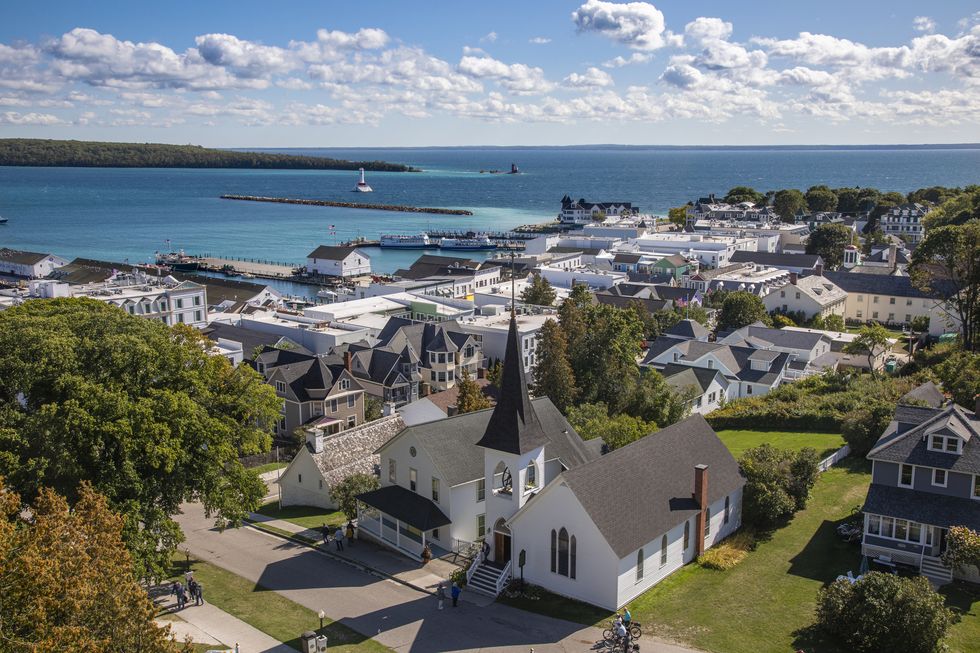mackinaw island town view from above with white church with steeple in foreground and water in background