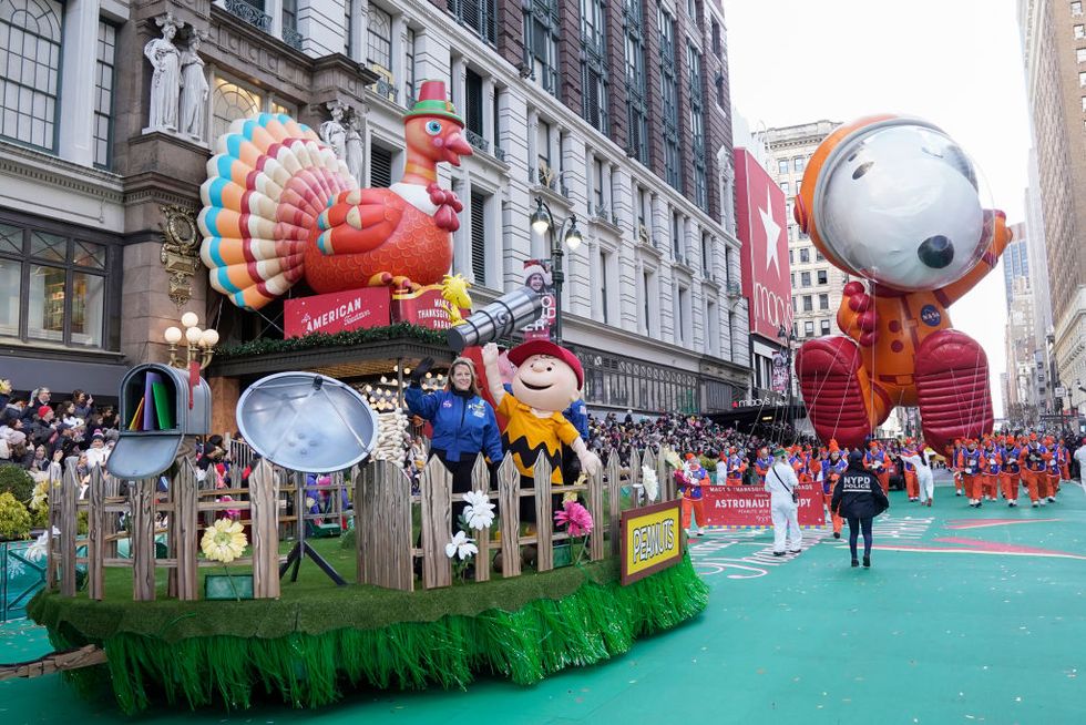 macy's thanksgiving day parade in new york city pictured with a charlie brown float with a turkey sitting on top and a giant snoopy float following
