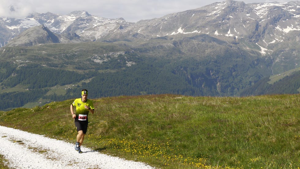a runner in a bright outfit participating in a mountain trail event surrounded by nature