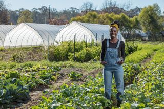 host jamila norman poses with crops at a farm in atlanta, as seen on homegrown, season 1