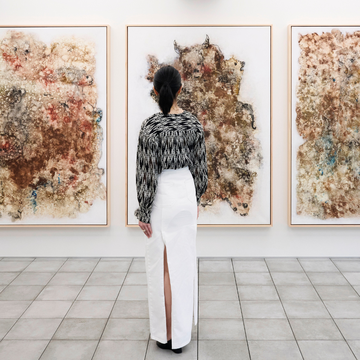 a person looking at a wall of paintings