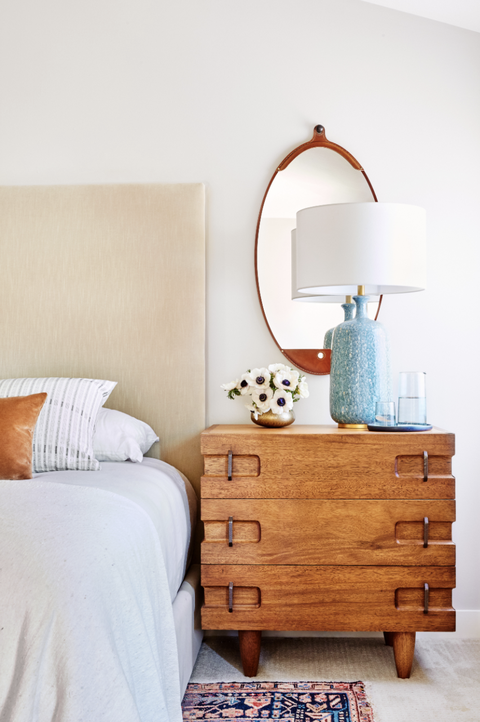 one side of the bedroom with a wood nightstand, lamp, and mirror
