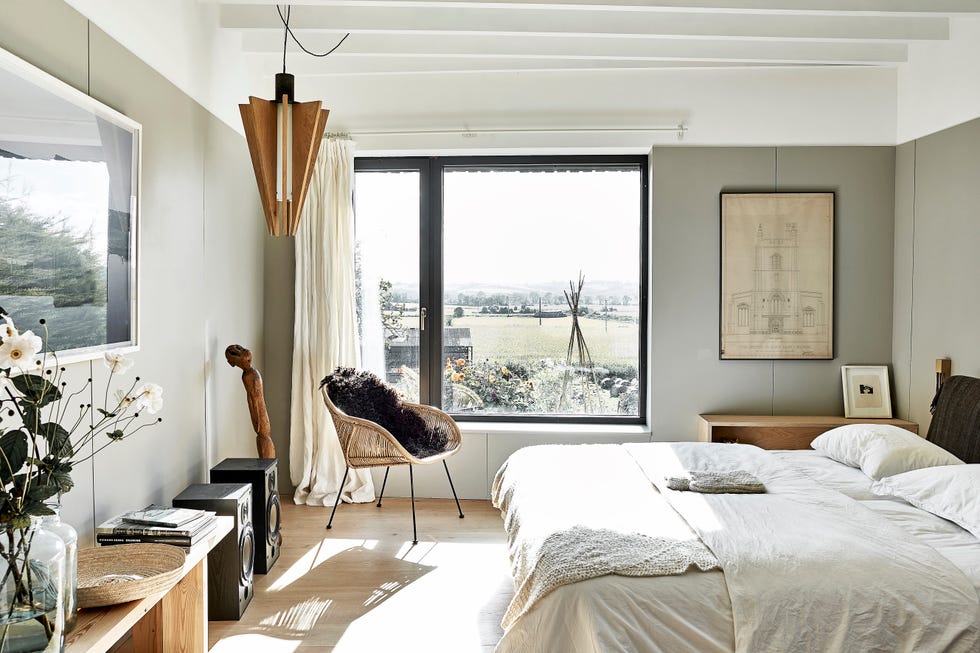 main bedroom painted in soft grey with large window overlooking the countryside