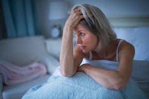 USA, New Jersey, Jersey City, Senior woman sitting in bed and suffering from insomnia