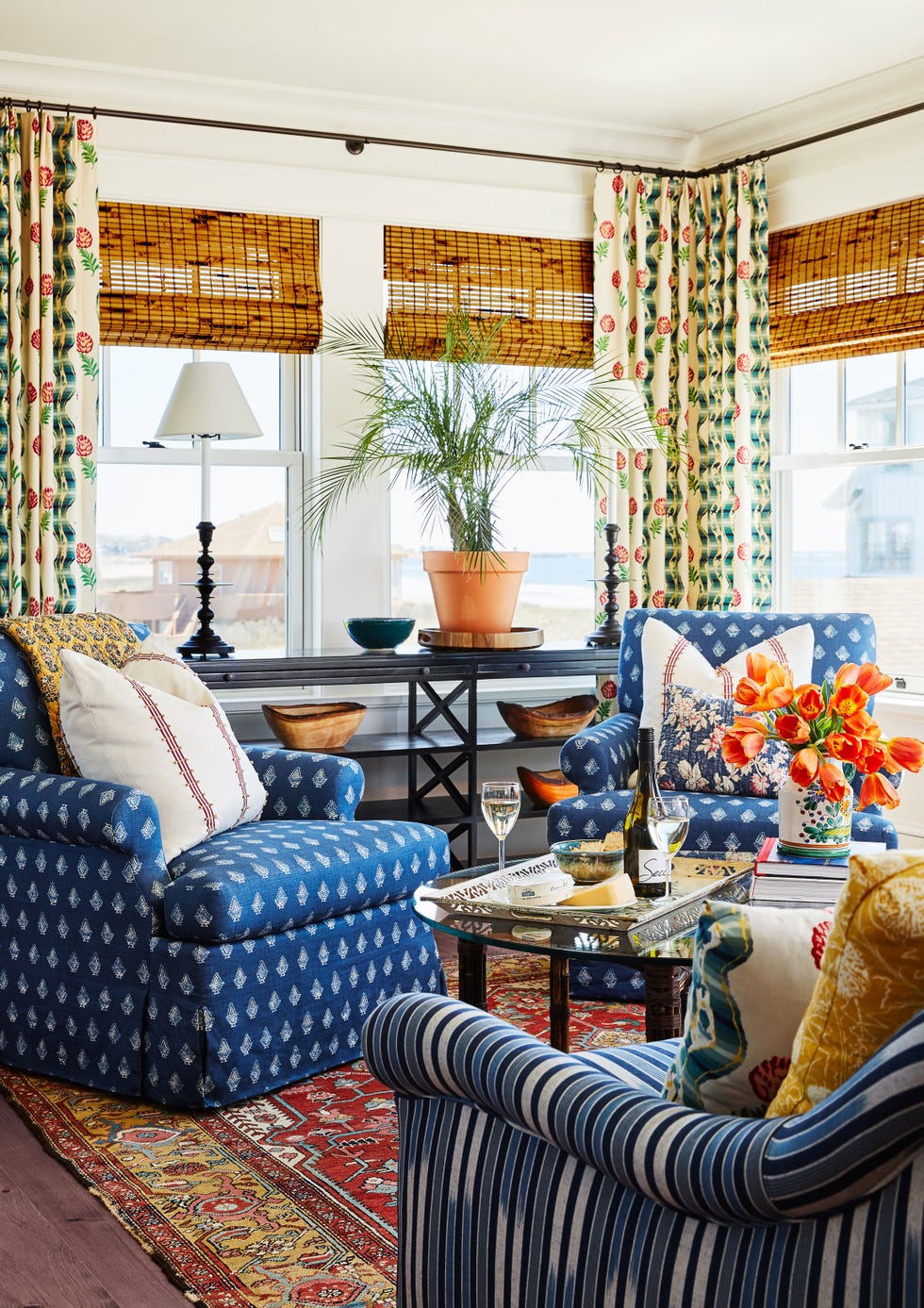 sitting room surrounded by windows with indigo block print fabric on chairs and colorful pillows and curtains