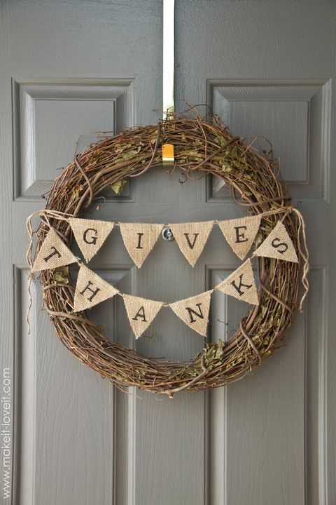 grapevine wreath with give thanks bunting on a gray door