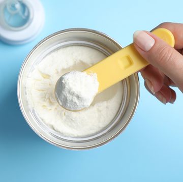 top view of hand scooping baby formula from a can