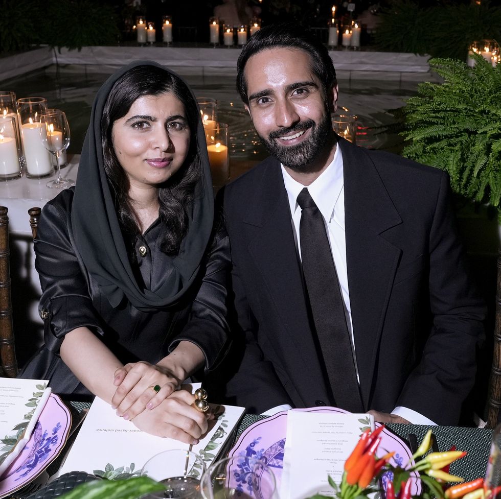malala yousafzai sitting behind a table and smiling alongside husband asser malik