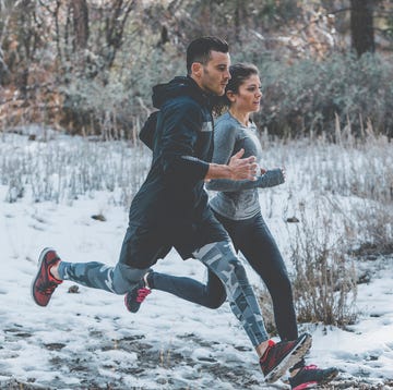 Male and female athletes running in forest during winter male and female athletes running in forest during winter