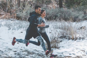 male and female athletes running in forest during winter