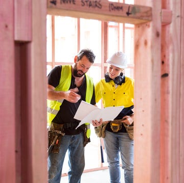 Male and female construction workers discuss the building plans inside the building site