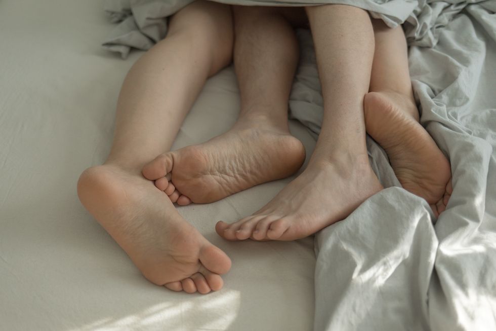 male and female feet in bed under blankets