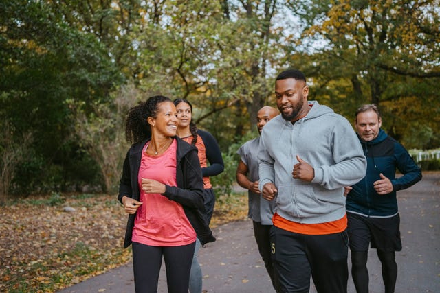 male and female friends jogging on road in park