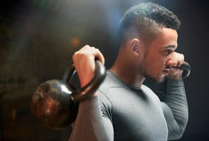 male athlete exercising with kettle bells